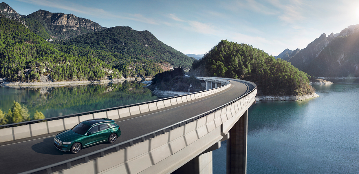 A photo captured from a distance of the Genesis Electrified GV70 driving