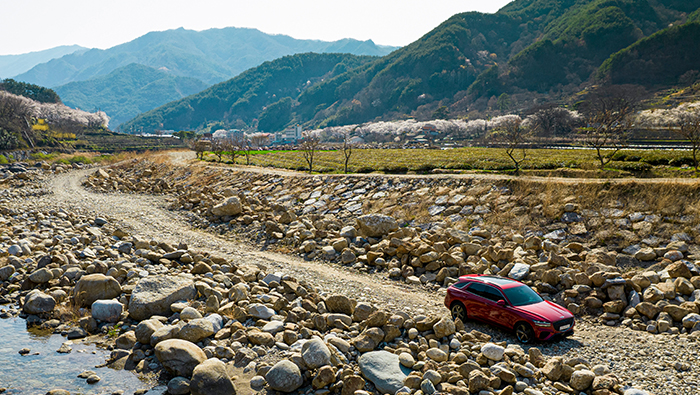 GV70 driving off-road between mountains and rivers