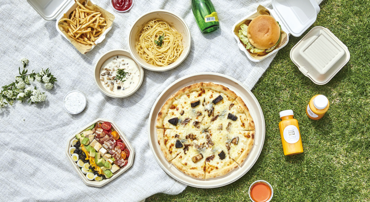 피자, 파스타, 샐러드, 햄버거, 주스 등 식음료가 피크닉 매트에 늘어선 모습