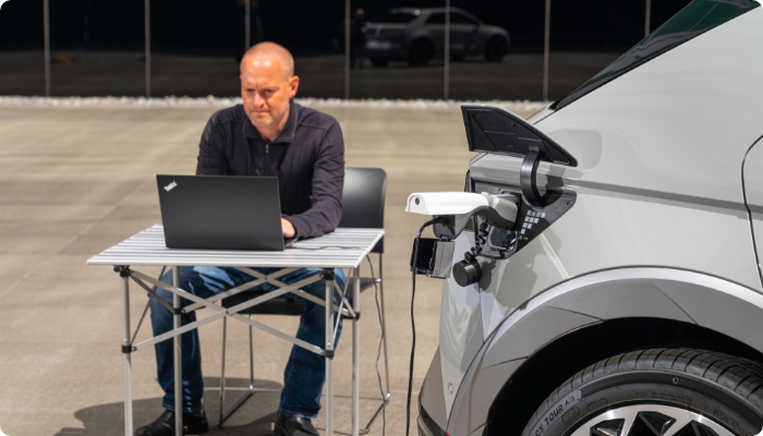 A man using a laptop by utilizing the V2L feature of the Ioniq 5