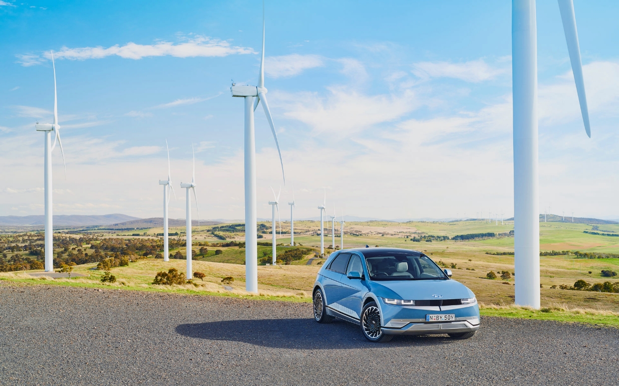 Hyundai Motor Company's eco-friendly electric vehicle, the Ioniq 5, stands in the background of a wind power plant
