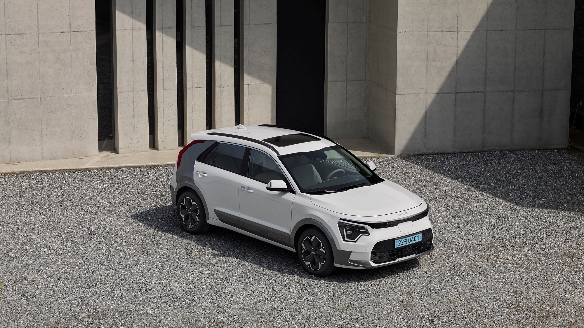 회색 건물 앞에 주차되어 있는 신형 니로 EV 전측면부