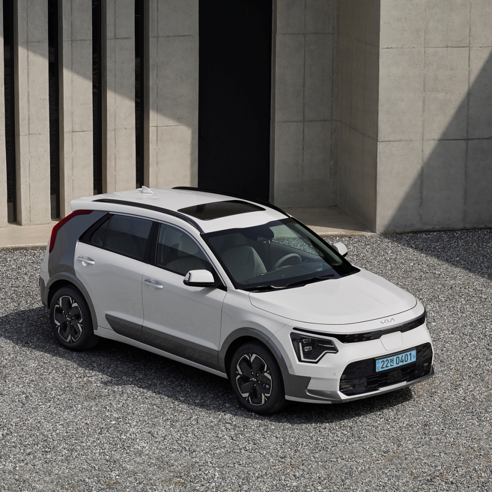 회색 건물 앞에 주차되어 있는 신형 니로 EV 전측면부