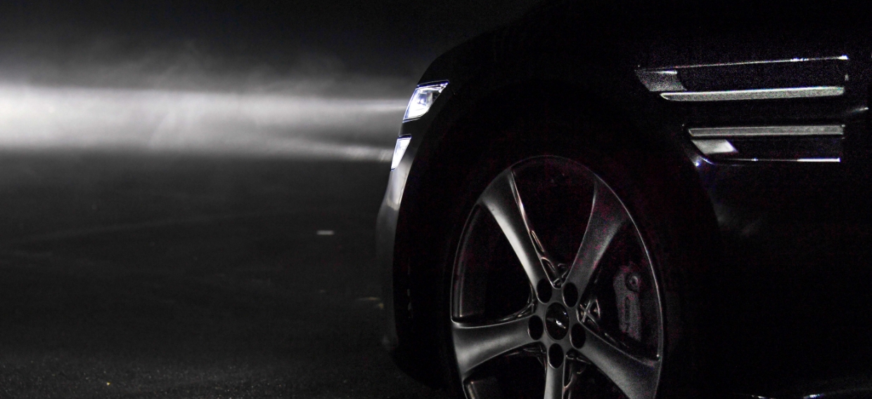 A car with its headlights on is standing in a dark place
