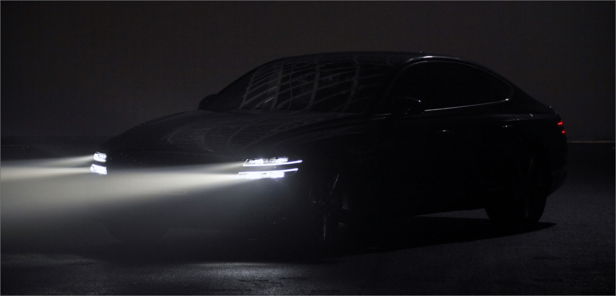 A car with headlights on is standing in a dark place