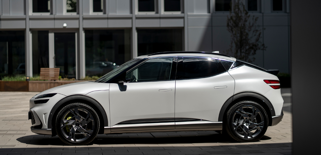 유럽의 어느 건물 앞에 주차되어 있는 제네시스 GV60의 측면 모습