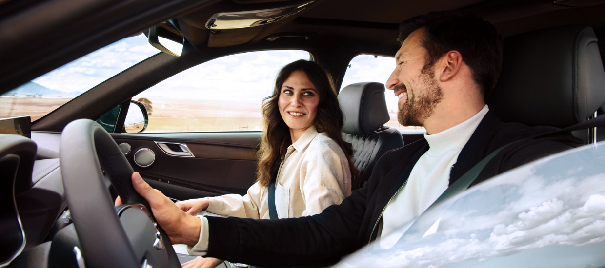 남녀가 자동차에 탑승해 웃으며 마주 보고 있다