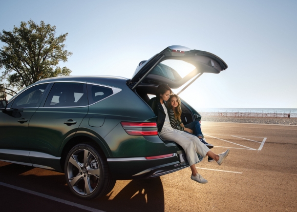 두 여성이 제네시스 GV80의 트렁크에 걸터앉아 있다