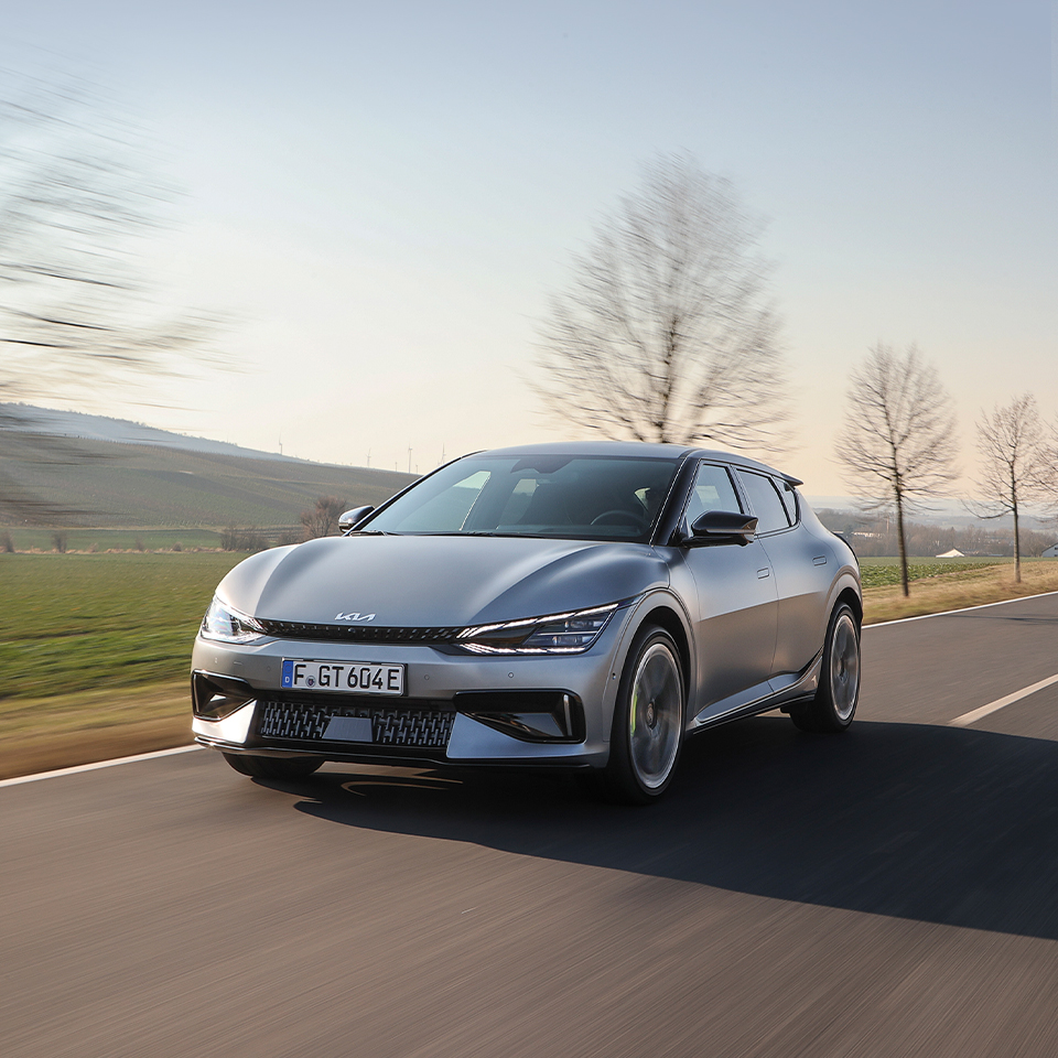 A view of the Kia EV6 GT driving down a European suburban road