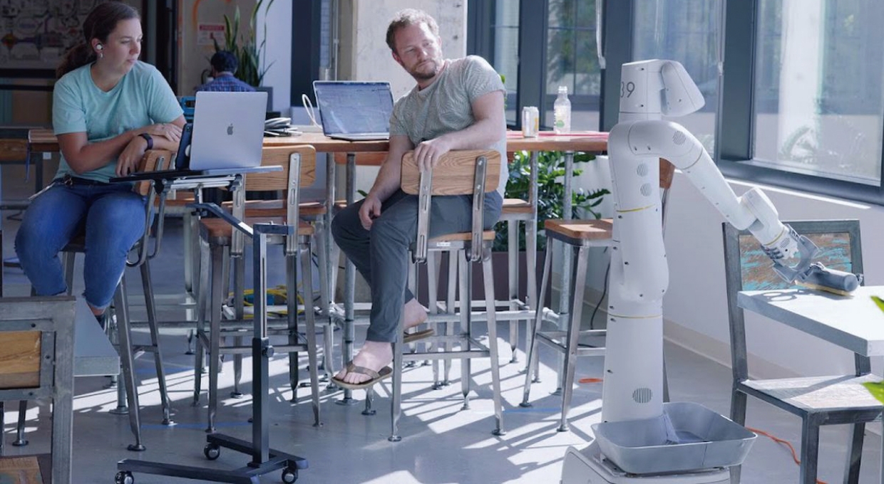 책상을 치우고 있는 로봇 ‘에브리데이’와 그 모습을 지켜보는 두 남녀의 모습