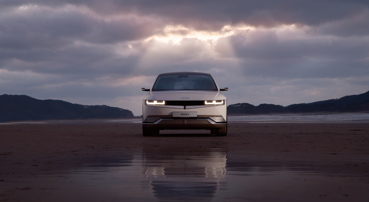 구름이 가득 낀 하늘 아래 정차 중인 현대자동차 아이오닉 5 전면부