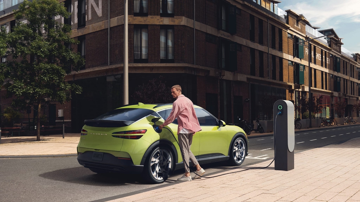 야외 충전소에서 한 남자가 GV60의 배터리를 충전하고 있는 모습