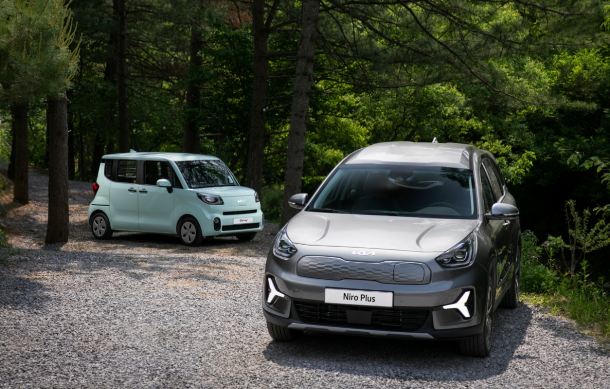 Front view of single-seater Niro Plus and Ray standing diagonally in the forest at campground
