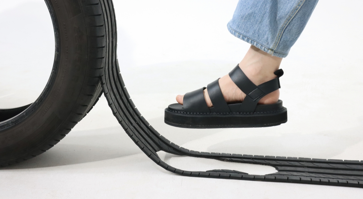 자동차 타이어와 가죽 샌들을 신은 다리