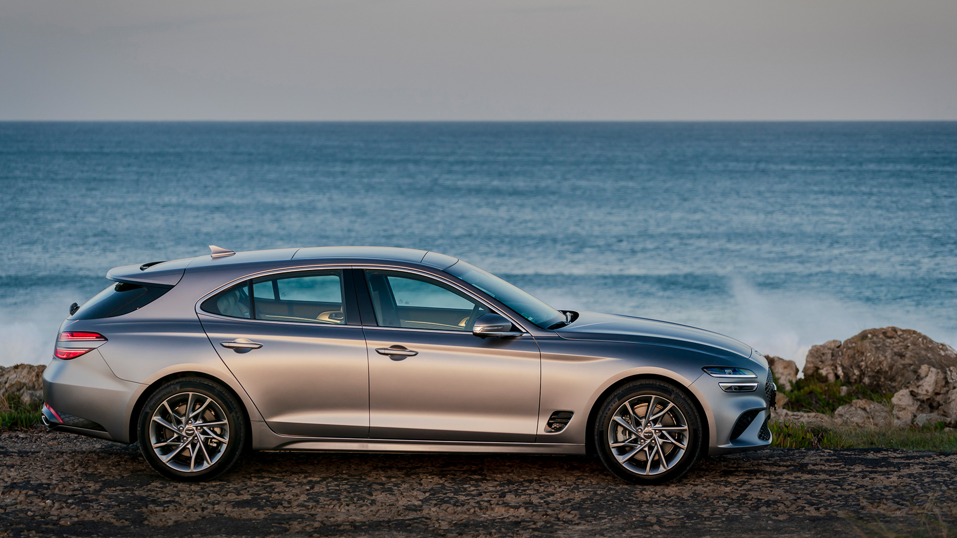 바닷가를 배경으로 서 있는 제네시스 G70 슈팅 브레이크의 옆모습