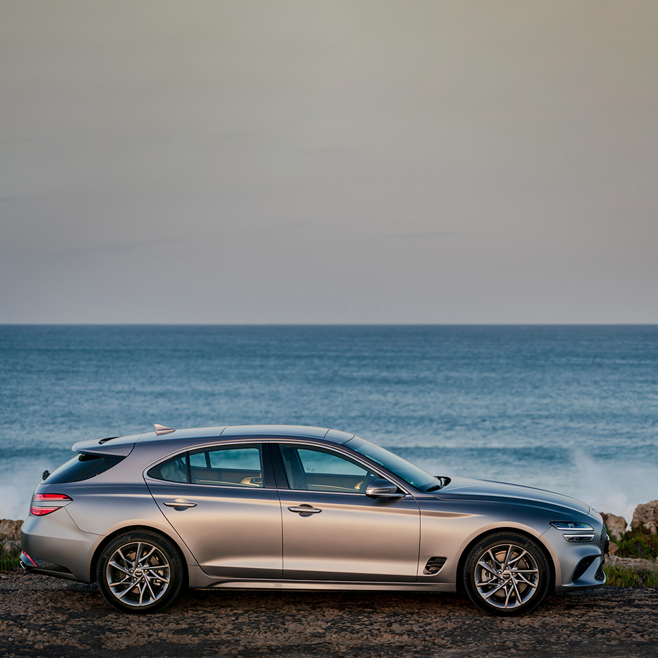 바닷가를 배경으로 서 있는 제네시스 G70 슈팅 브레이크의 옆모습