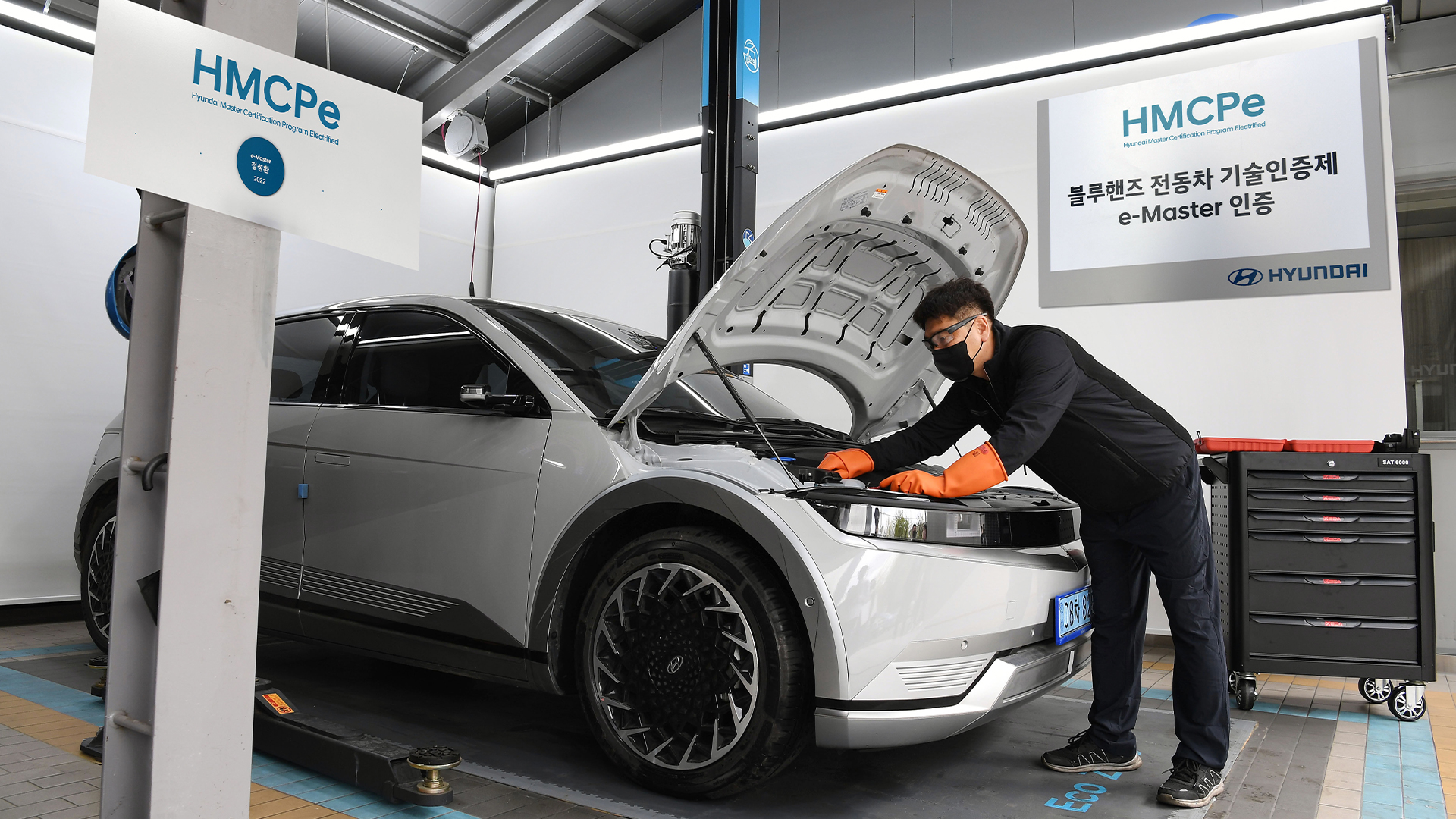 A mechanic is opening the bonnet of an electric car and inspecting the vehicle