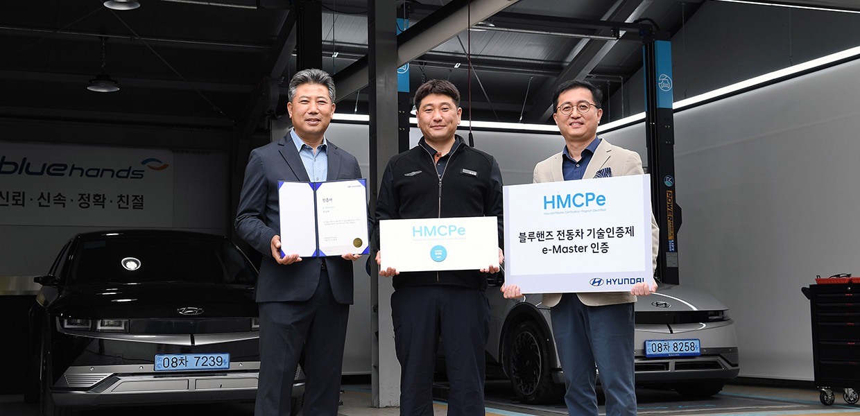 Electrified mechanics standing holding a train master certification program sign