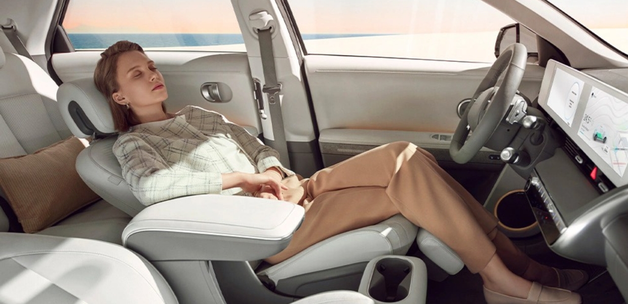 A woman is resting on the IONIQ 5 with a seat laid flat.