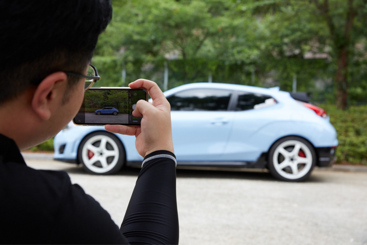 스마트폰 카메라로 자동차를 촬영하고 있는 인스타그래머