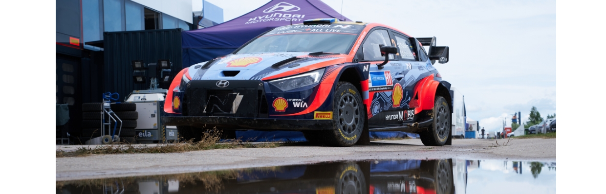 An i20 rally car is reflected in a puddle of rain