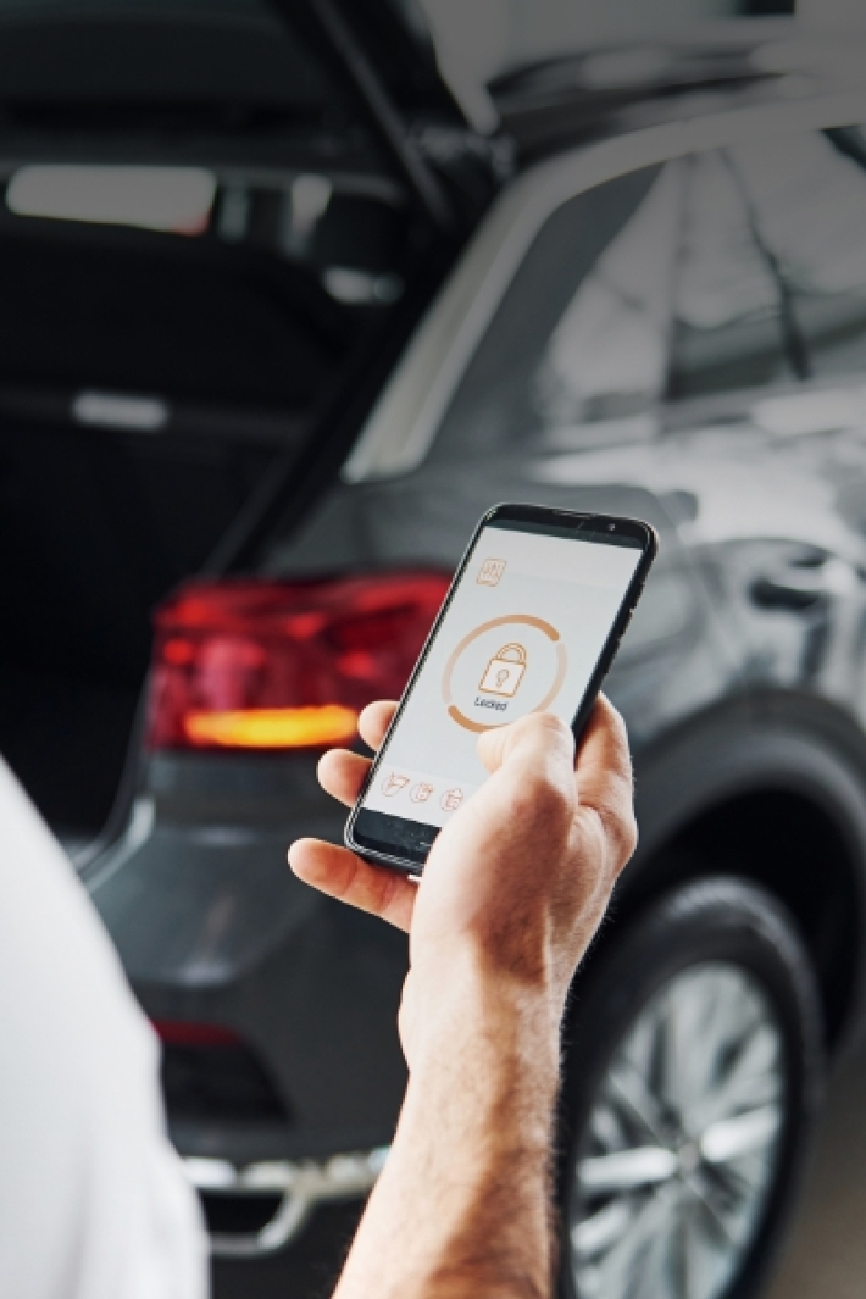 한 사람이 자동차 근처에서 스마트폰을 조작하고 있다