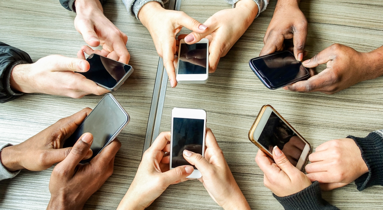 테이블 위에 휴대폰을 쥔 손을 올려 놓은 사람들