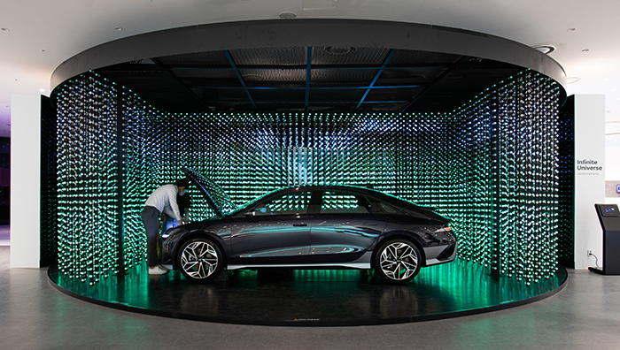 A visitor looking at the IONIQ 6 and the car displayed with the crystal LED in the background