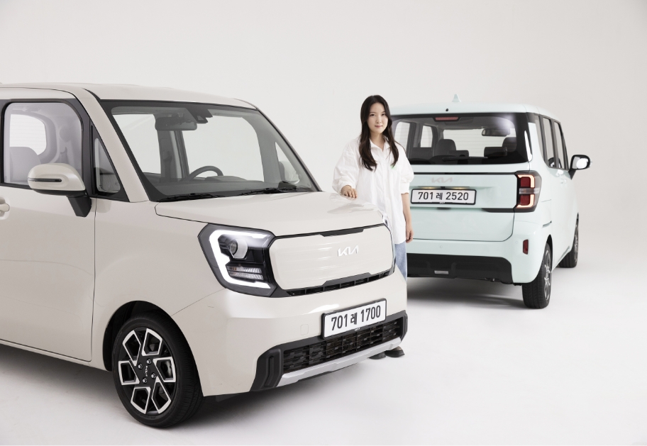 스튜디오에 전시되어 있는 더 뉴 기아 레이의 전측면 모습과 후측면 모습, 그리고 디자이너의 모습