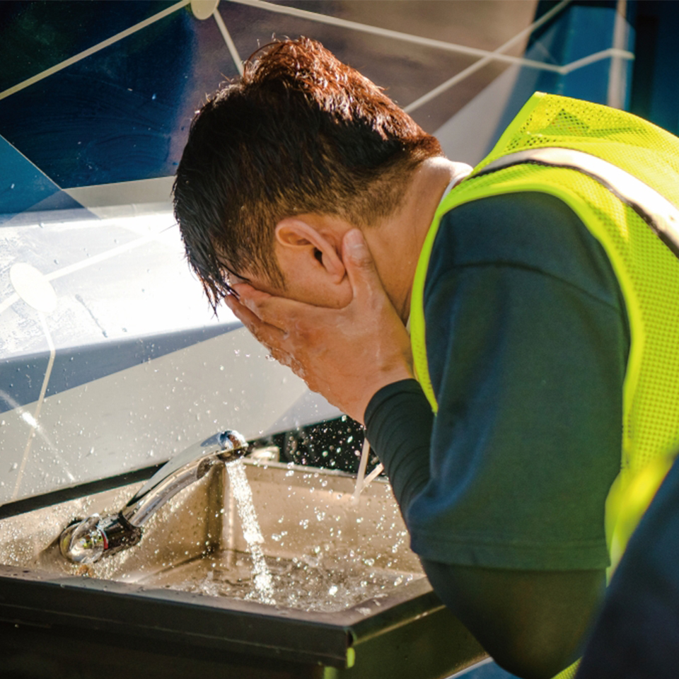A sanitation worker washing face in a hydrogen cleaning truck