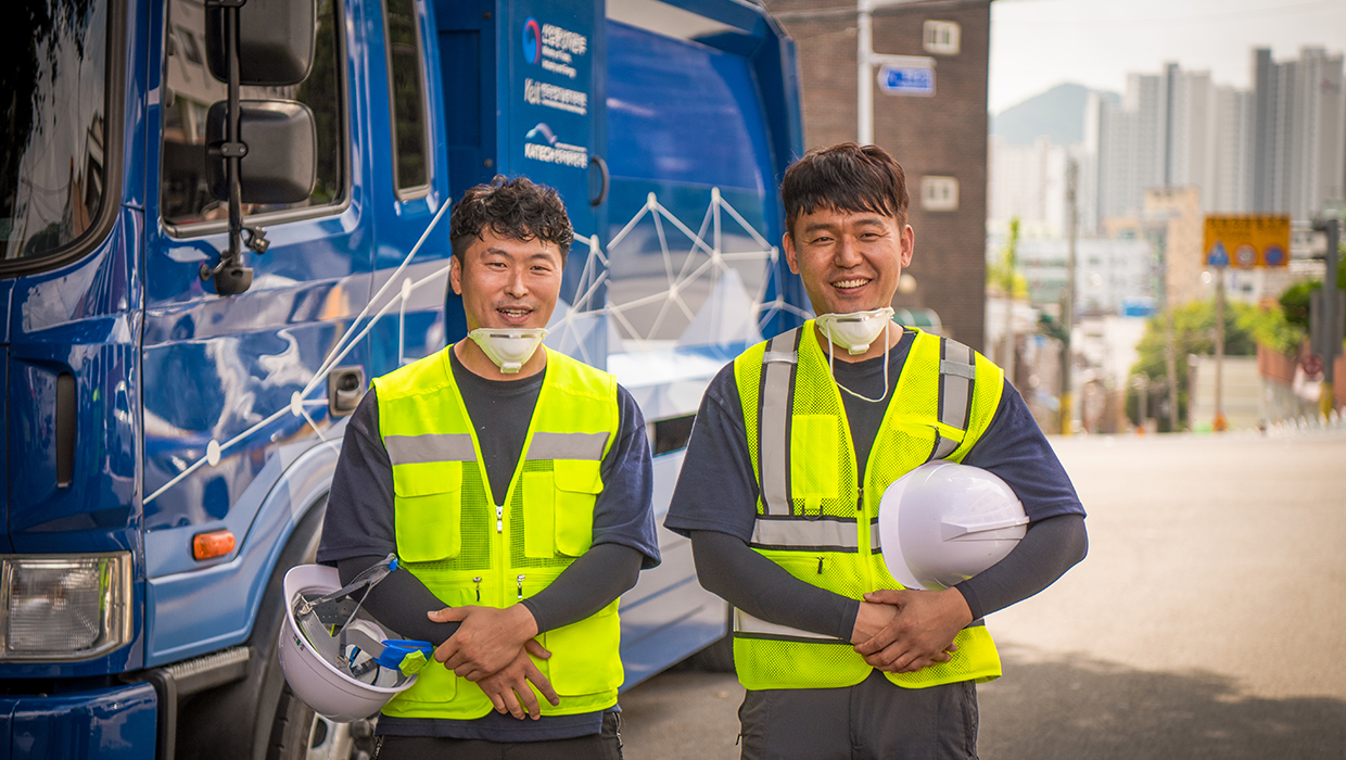 A sanitation worker smiling in front of a hydrogen cleaning truck