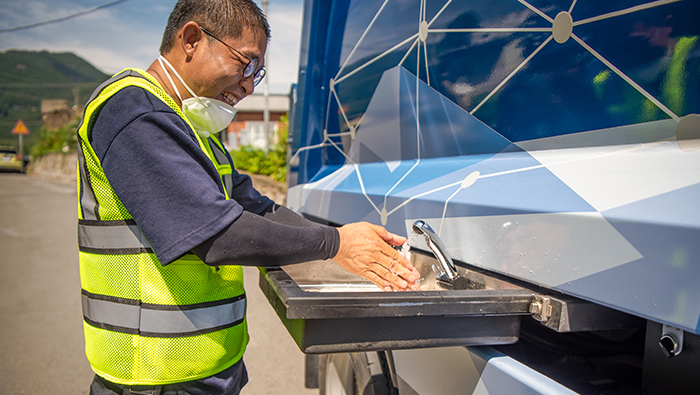 A sanitation worker washing hands in a hydrogen cleaning truck
