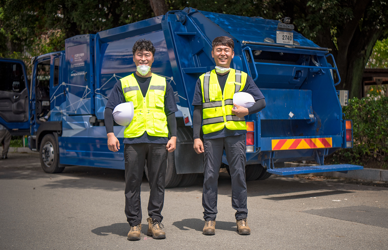 A sanitation worker smiling in front of a hydrogen cleaning truck