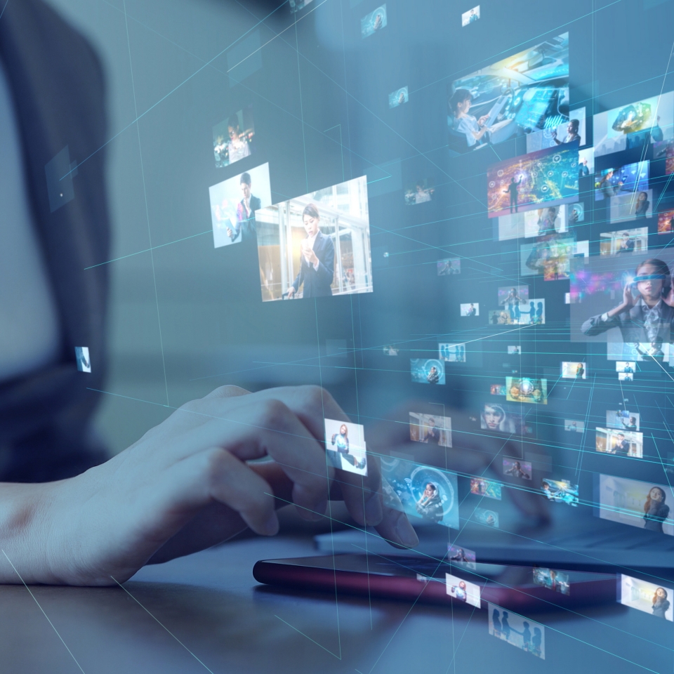 노트북을 만지는 손과 여러 화면들이 허공에 떠 있는 모습