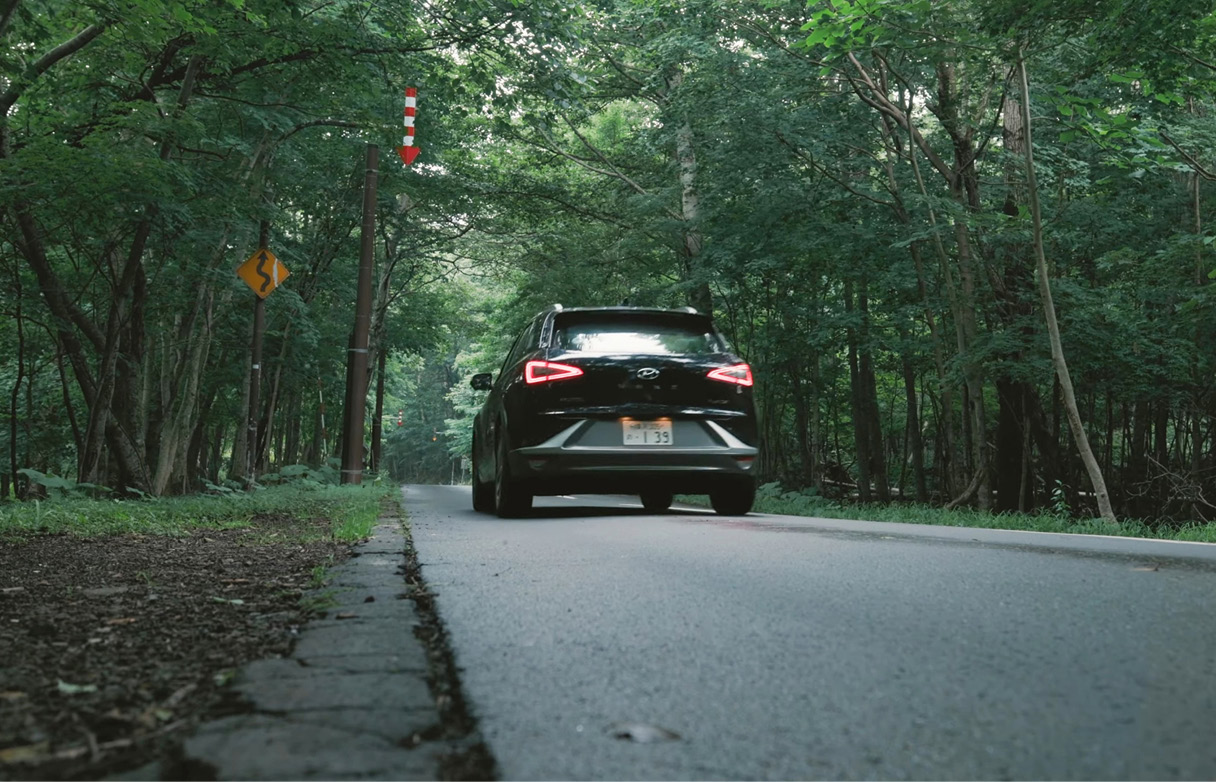 숲속 길을 지나가고 있는 현대 넥쏘