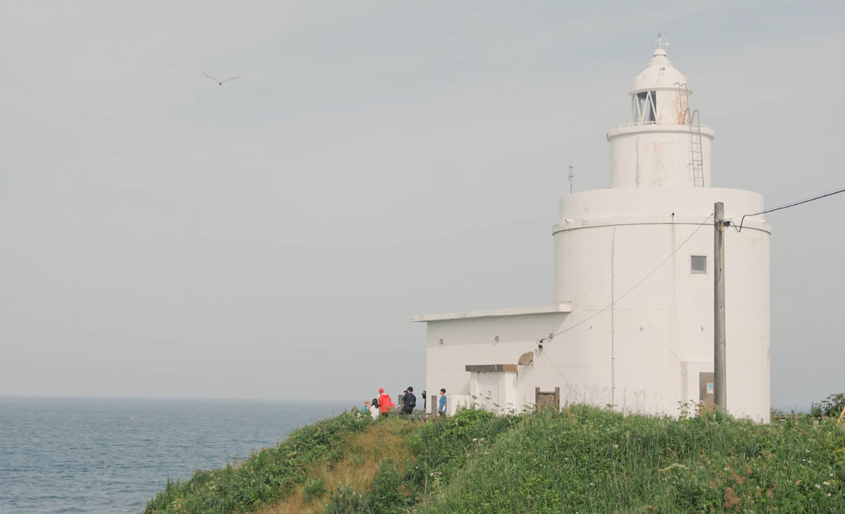 Gil-soo Seo's family is looking out to the sea in front of the lighthouse at the destination
