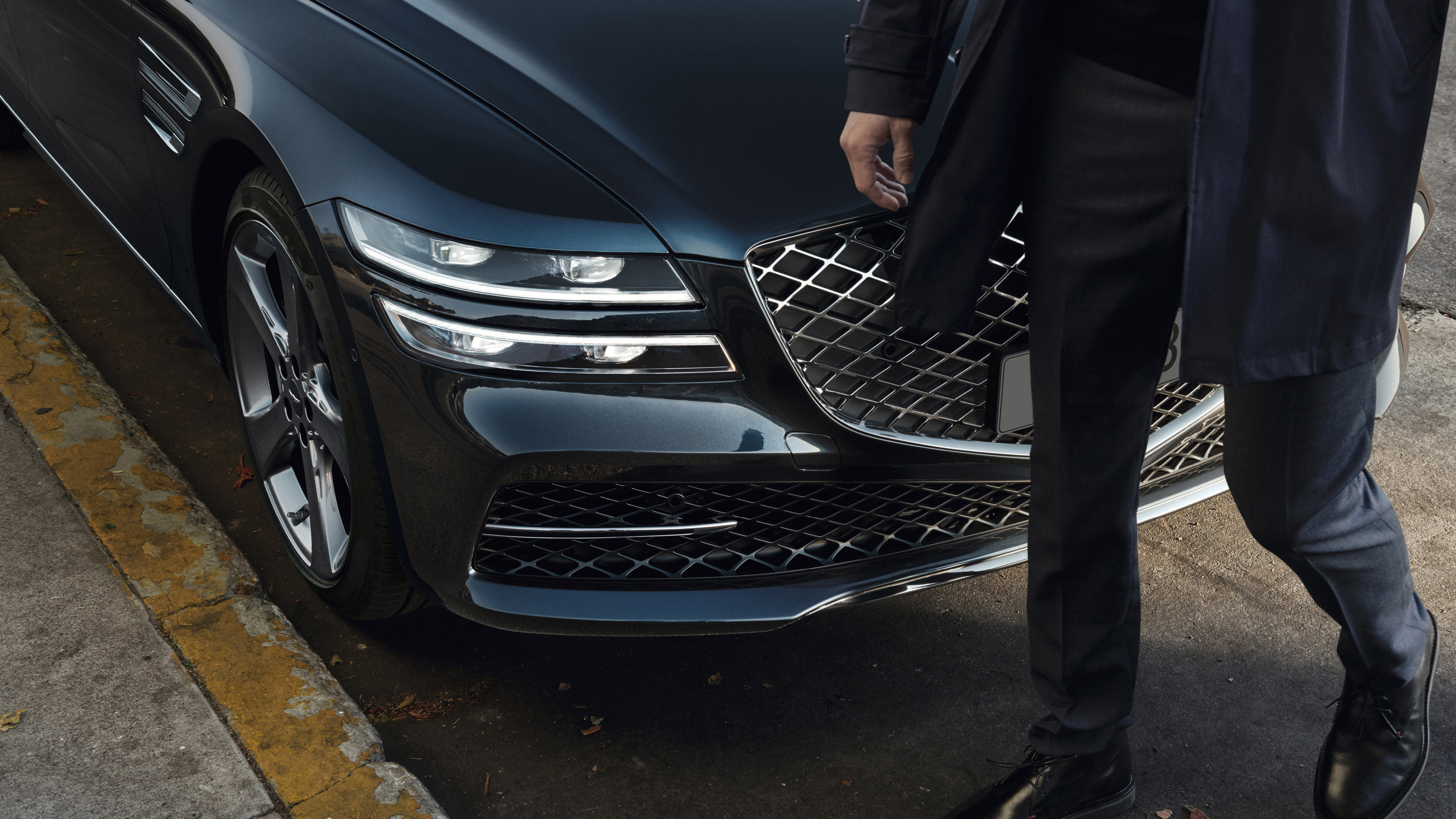 A pedestrian is passing in front of the Genesis G80