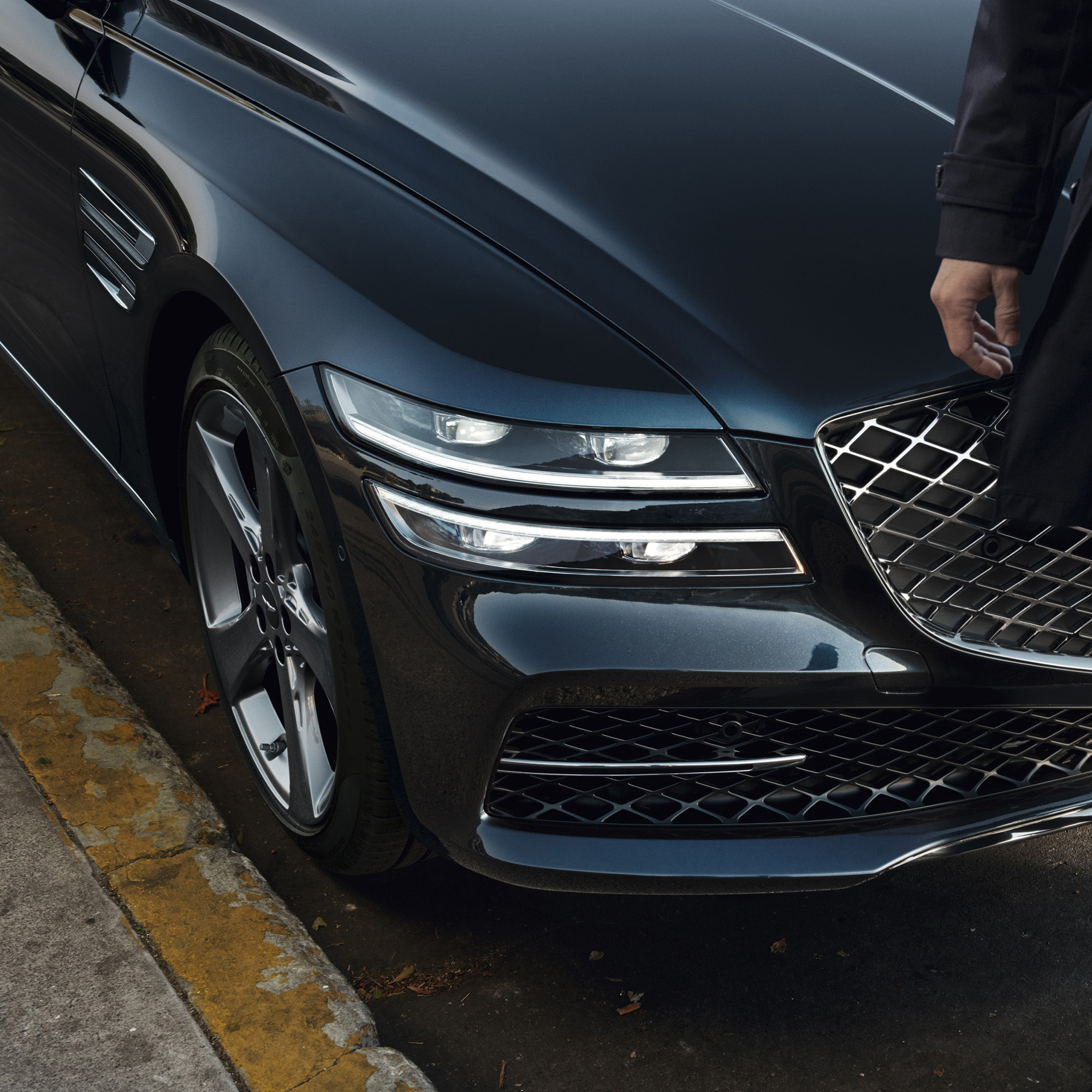 A pedestrian is passing in front of the Genesis G80