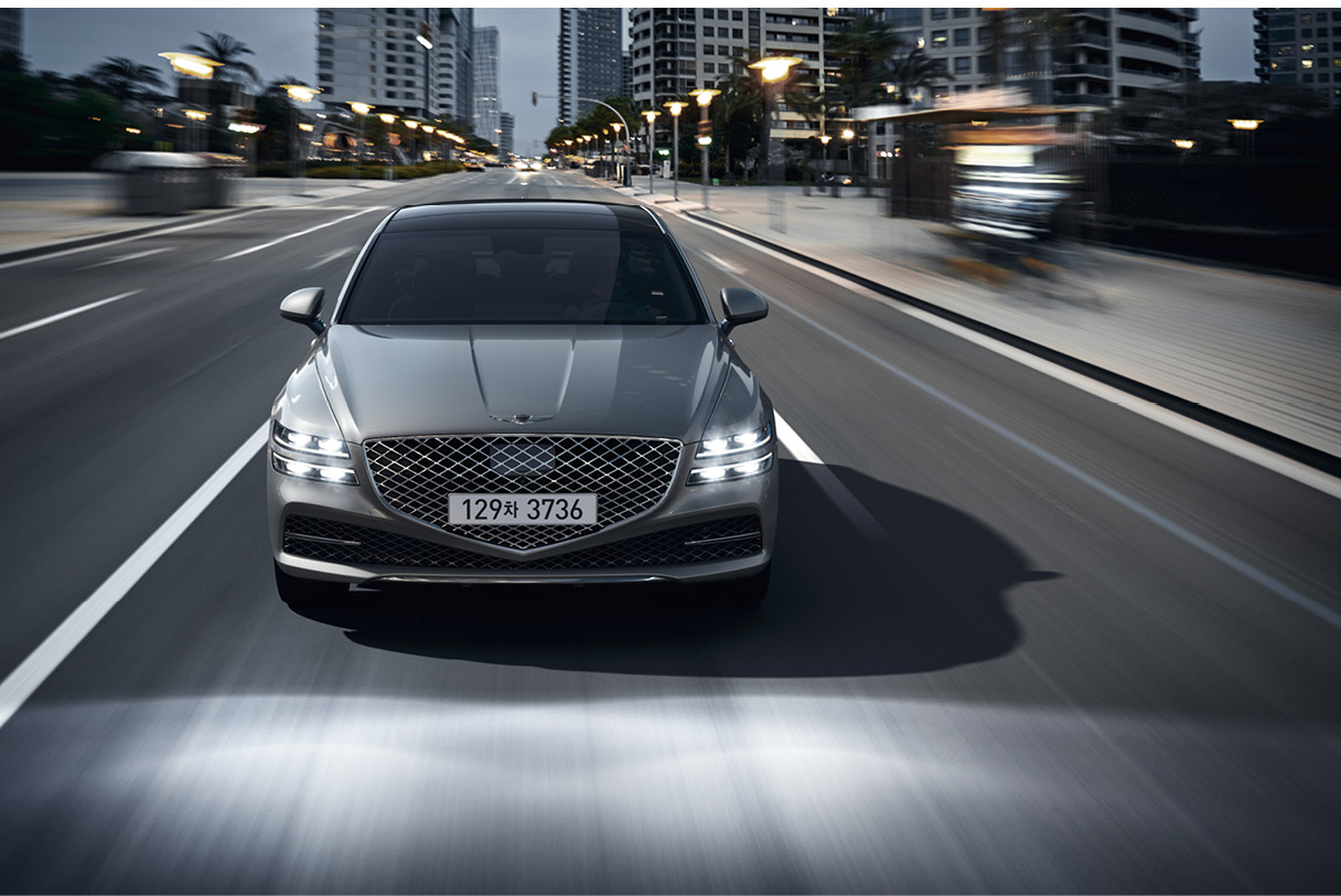 Genesis G80 in motion with headlamps on