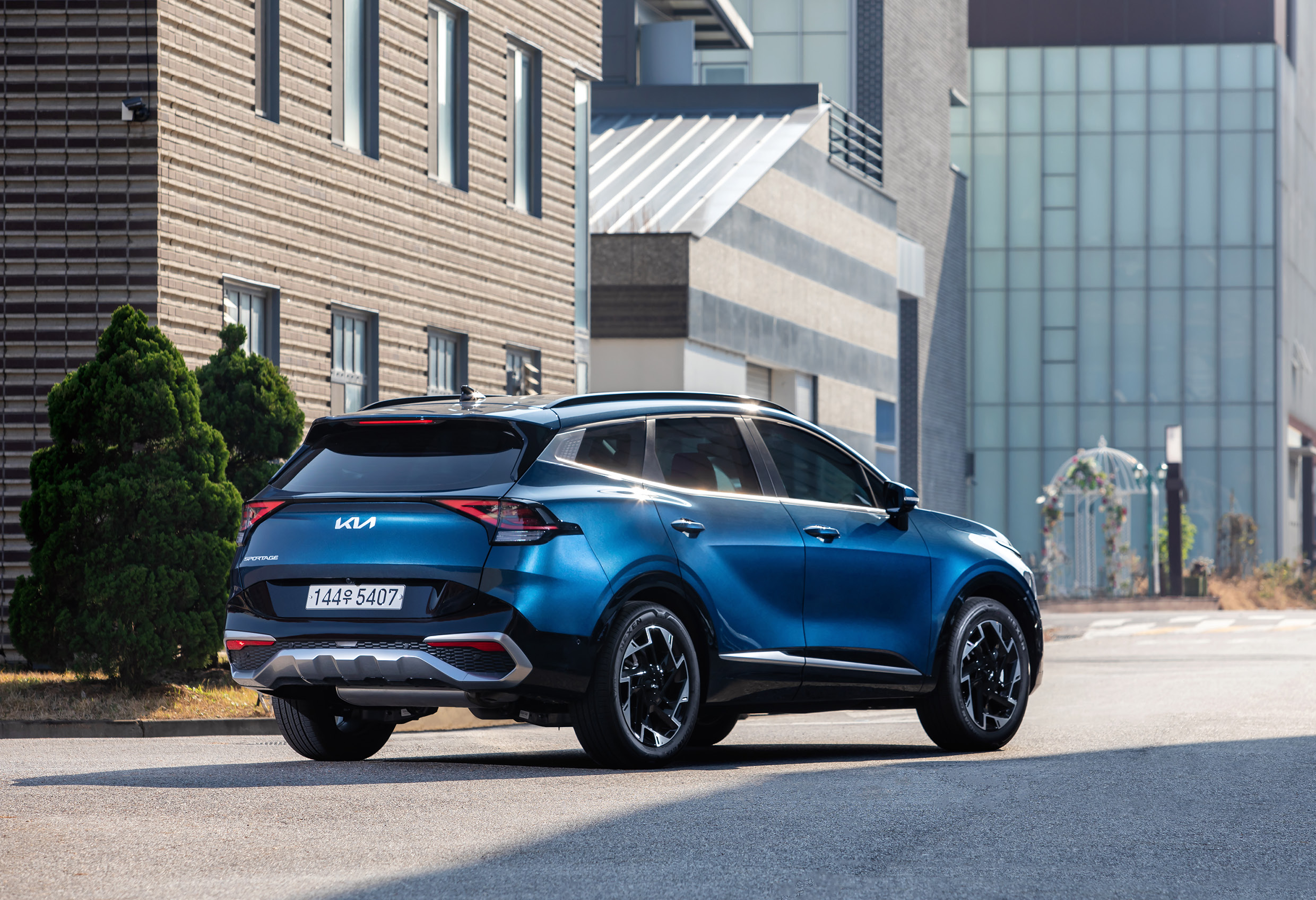 모던한 건물 사이에 있는 스포티지 LPi의 후측면 모습 이미지