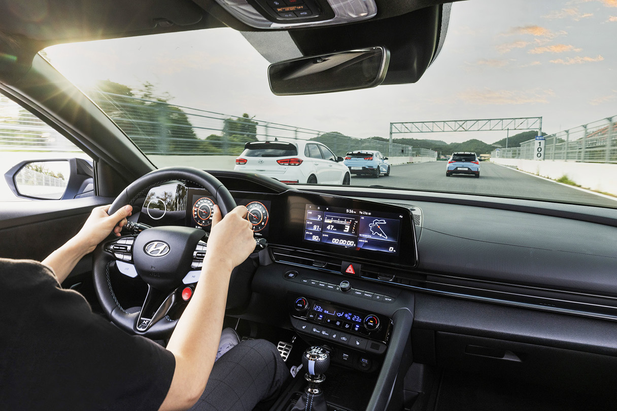 현대자동차 아반떼 N의 운전석과 앞유리 너머로 보이는 N 모델들의 뒷모습