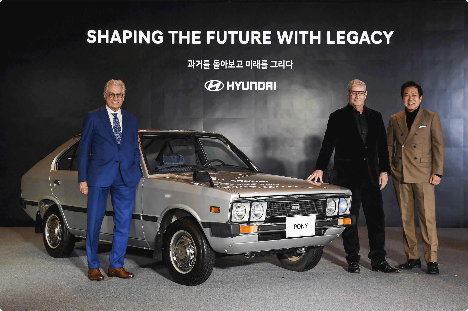 Giorgetto Giugiaro, Luc Donckerwolke, Chief Creative Officer of Hyundai Motor Group, and Sang-yup Lee, Executive Vice President and Head of Hyundai Motor's Global Design Center, standing next to a Pony.