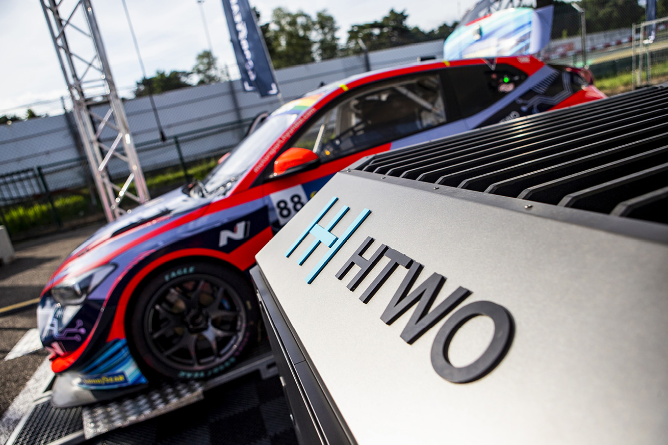 A Veloster race car standing side by side with a hydrogen fuel cell generator