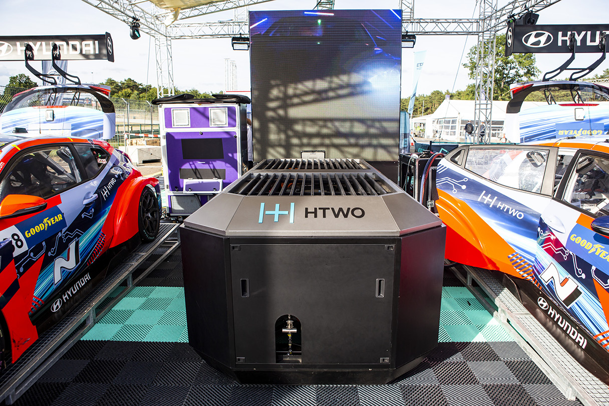 A Veloster race car standing side by side with a hydrogen fuel cell generator