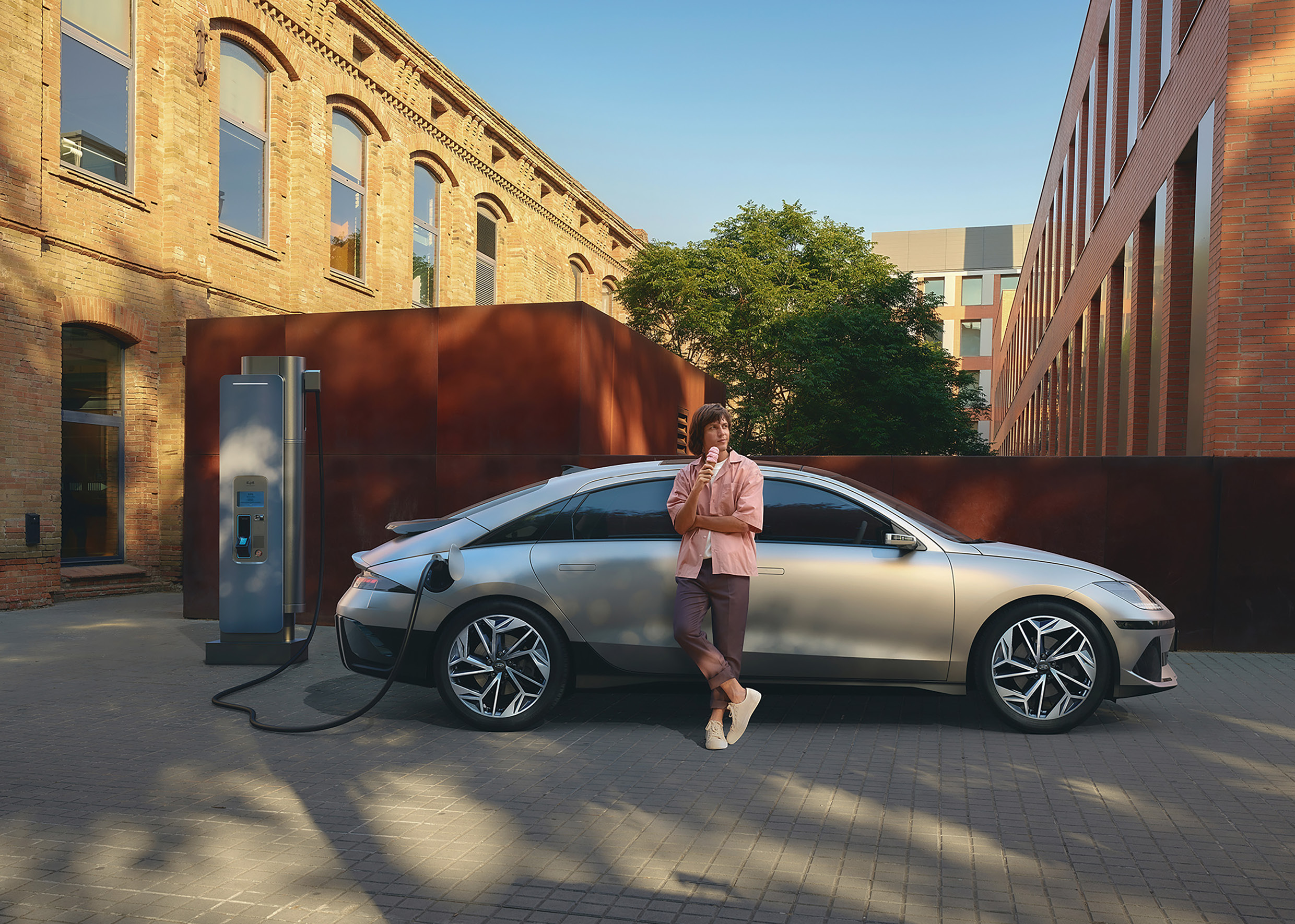 아이오닉 6를 충전하며 사람이 차에 기대어 있는 모습