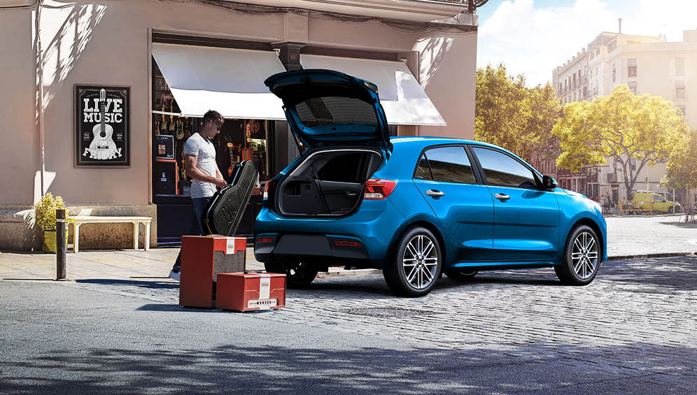 한 남성이 기아 리오의 해치 게이트를 열고 짐을 적재하고 있다