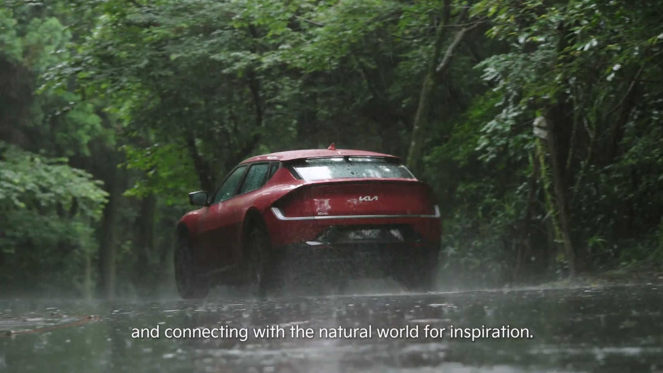 비가 쏟아지는 숲 속에 서있는 기아 EV6의 모습