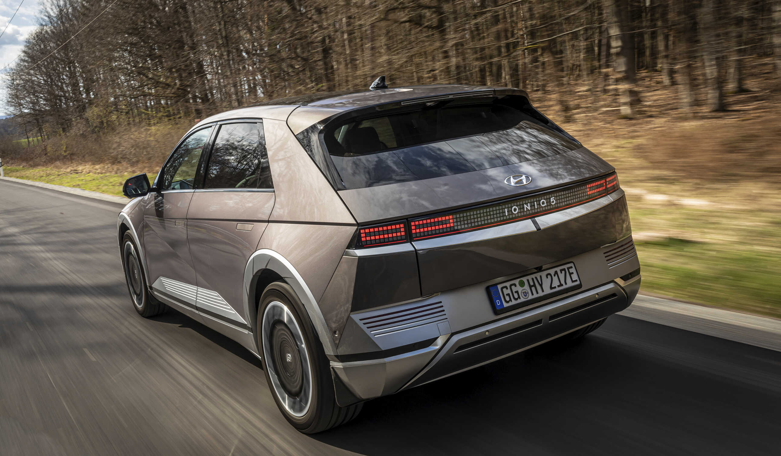 아이오닉 5가 한적한 유럽 교외 도로를 주행하는 후측면 모습