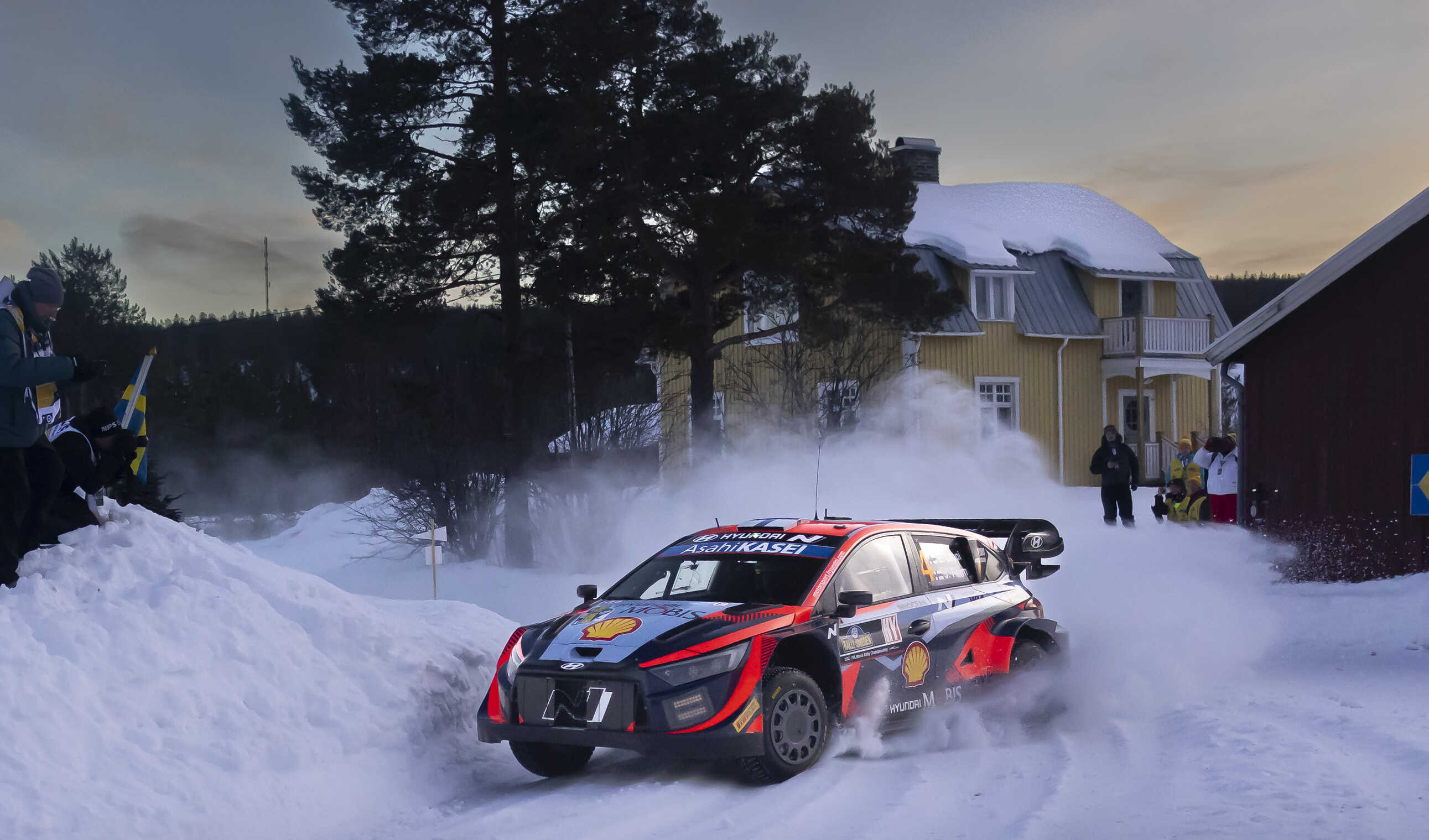 A Hyundai rally car exiting a corner in white snow