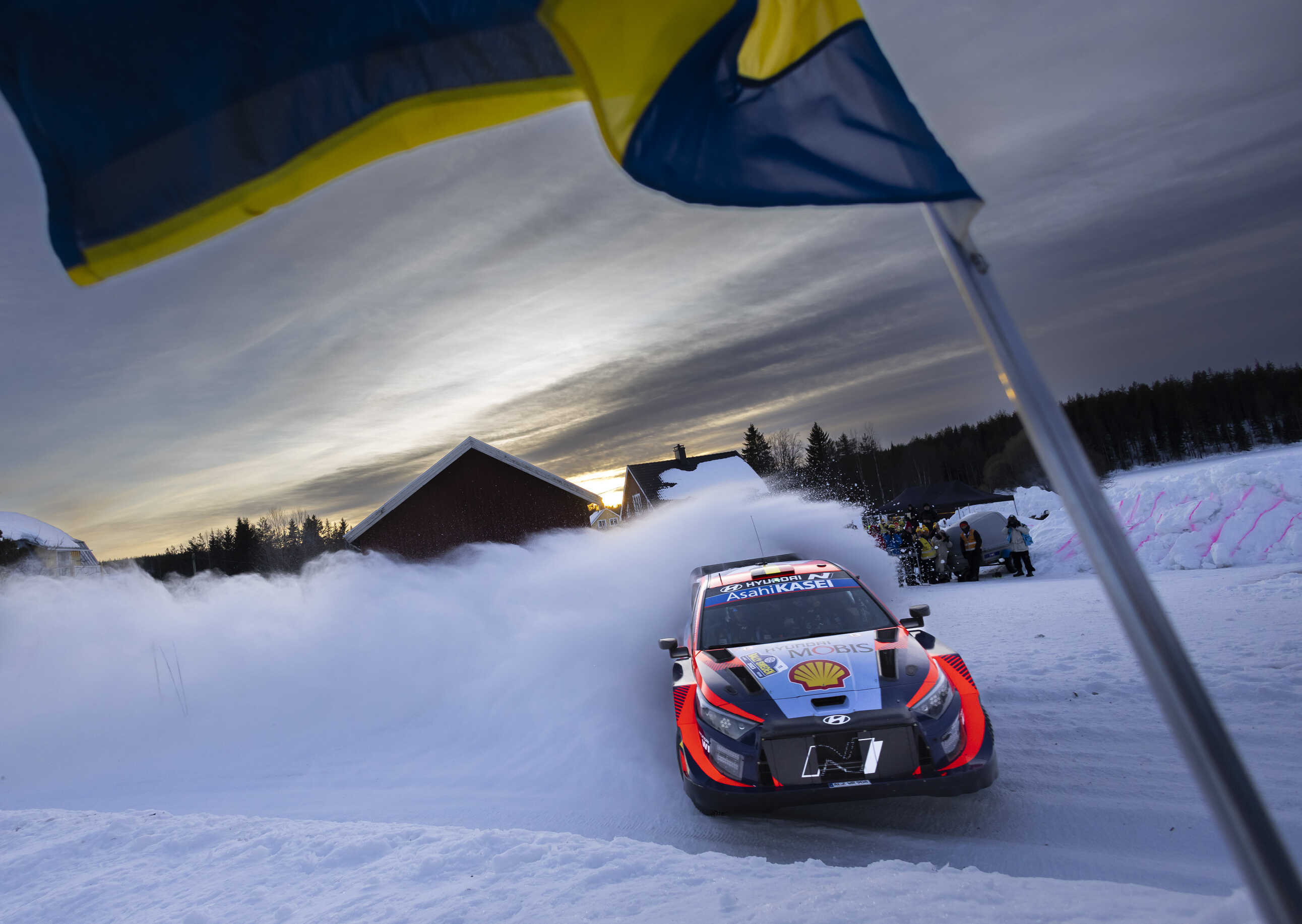 Rally car drifting through a snowy corner